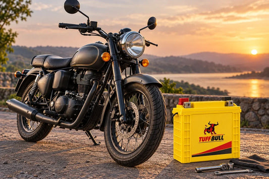 Tuff Bull two-wheeler battery displayed beside a classic-style black motorcycle at sunset